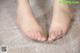 A pair of bare feet on a carpeted floor.