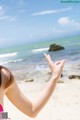 A woman in a pink bikini standing on a beach.