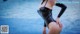 a woman in a black wet suit standing next to a pool