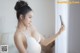 A woman in a white bra holding a cell phone.